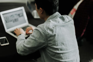 member working on laptop in the open coworking space with fellow coworkers